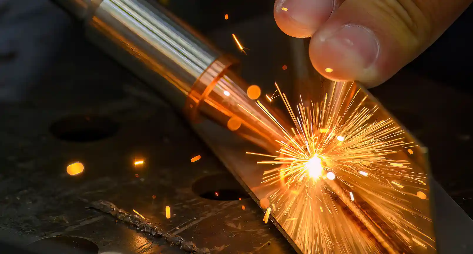 Industrial laser welding machine in action, showcasing precision welding with sparks and bright light in a manufacturing setting.